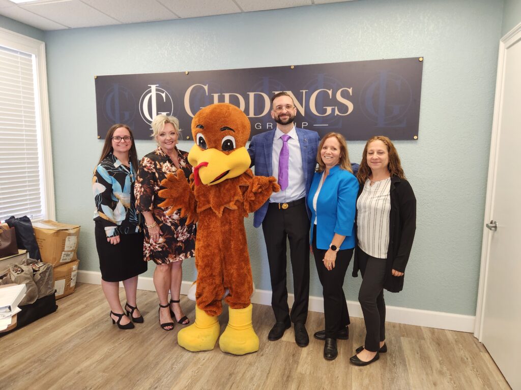 Giddings Law Group team posing with a Thanksgiving turkey from Seeds of Hope, supporting community outreach in Brandon and Hillsborough County, Florida.
