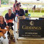 The Giddings Law Group Team at the Hillsborough County Fair Grounds pictured next to a dog named Willow.
