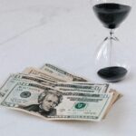 Hourglass near Heap of American Dollars